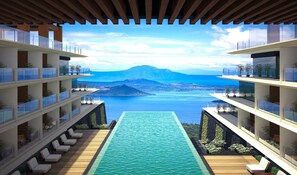 Un hotel moderno con piscina, diversi balconi e vista su montagna e mare.
