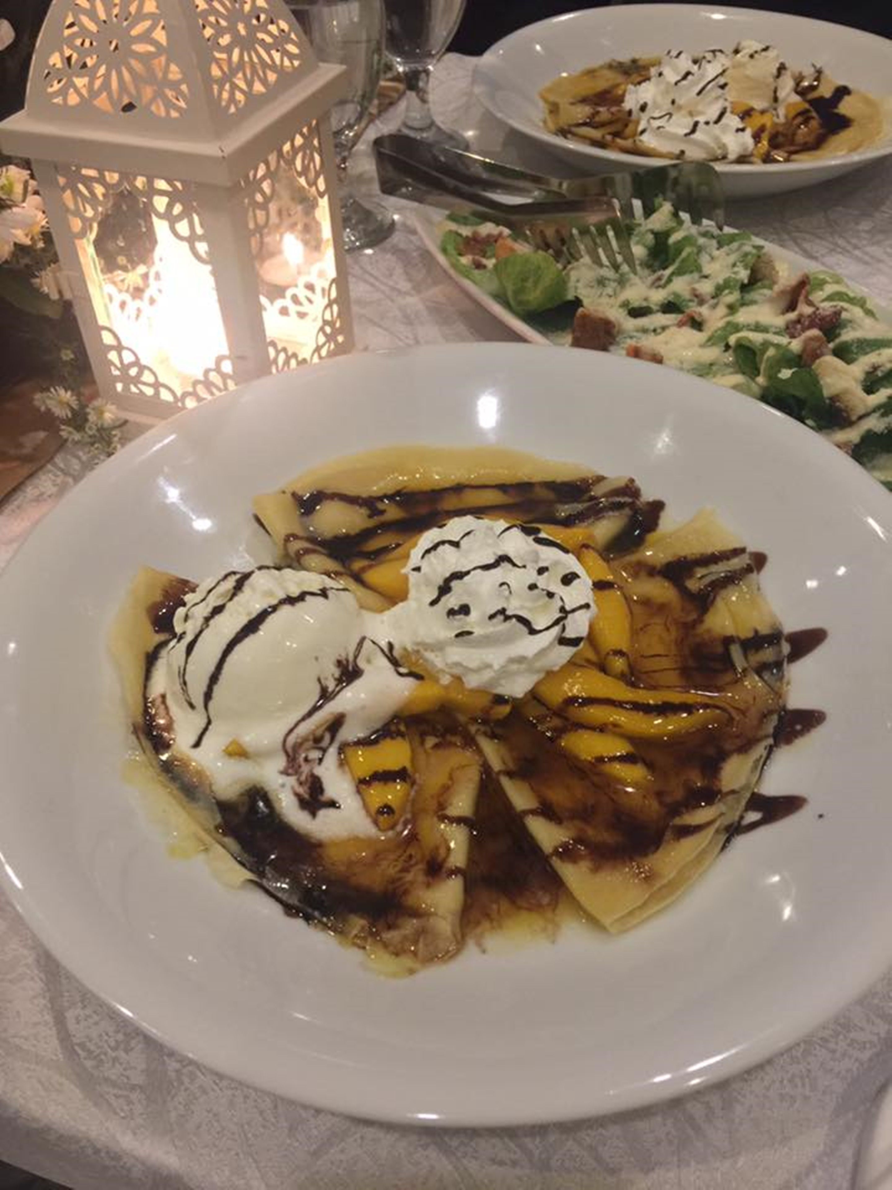 A dessert plate with a banana slice and whipped cream on a white plate.