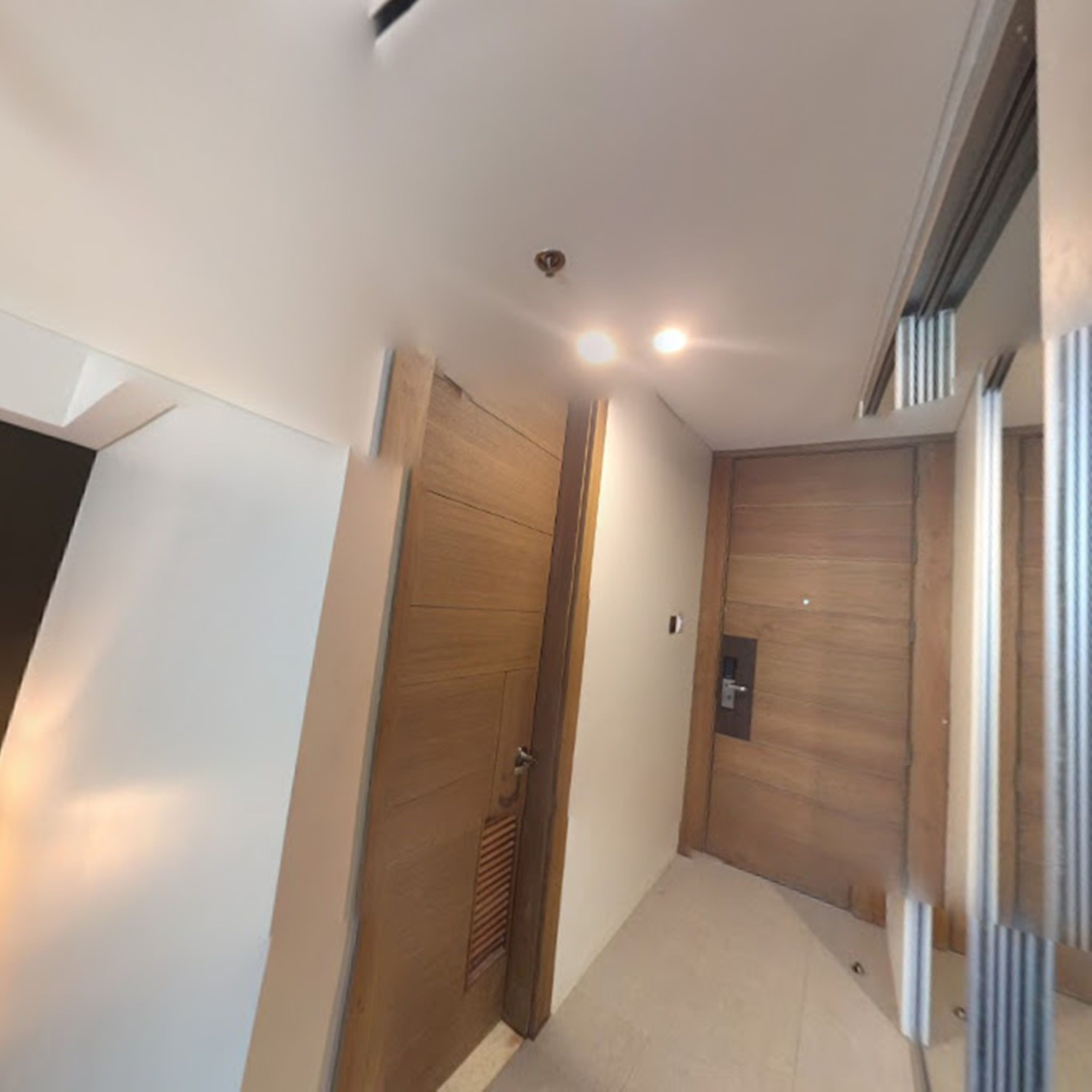 A hallway with a wooden door, a light switch, and a vent on the wall.