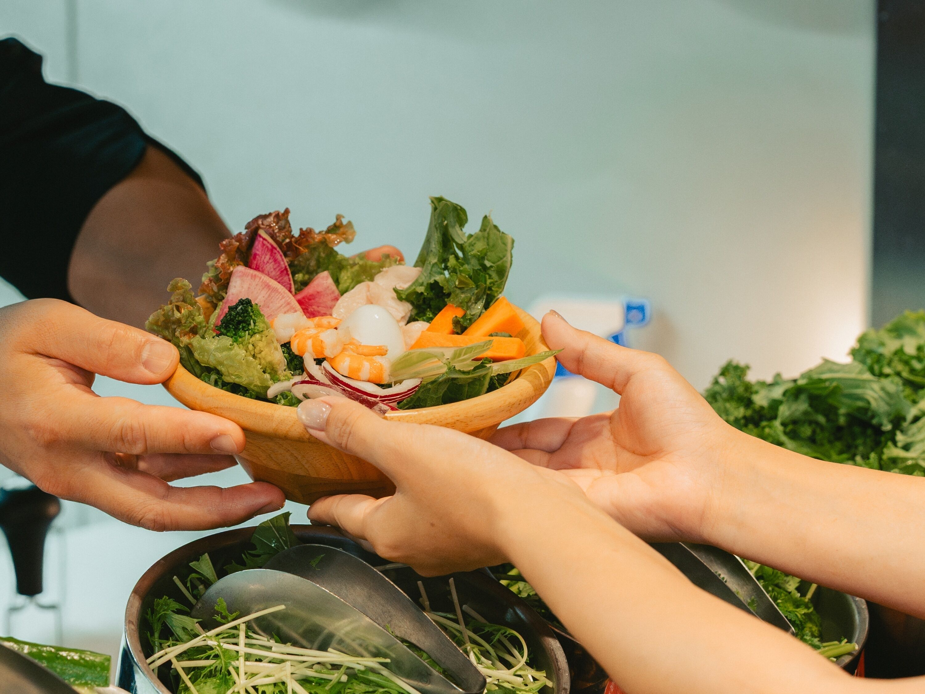 A person holding a bowl of salad with various vegetables and a boiled egg.