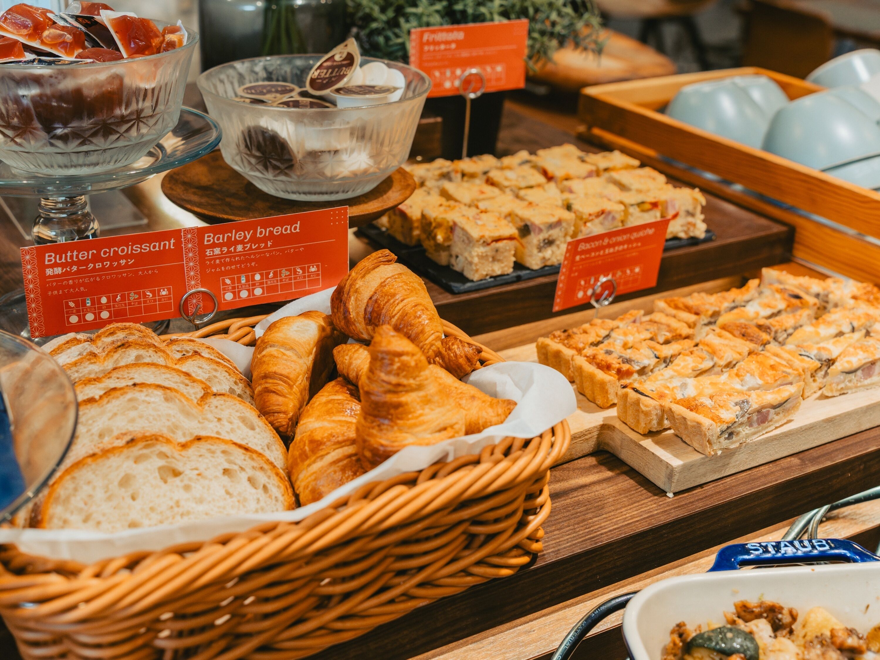 A buffet with various baked goods including bread, croissants, and pastries.
