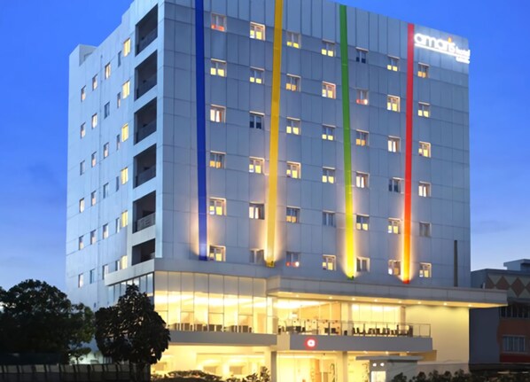 A multi-story hotel with a modern facade, illuminated windows, and a prominent sign.