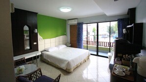 A hotel room with a bed, a dining table with chairs, a small kitchen area, and a balcony with a view. - RangRong Hotel (Patong)