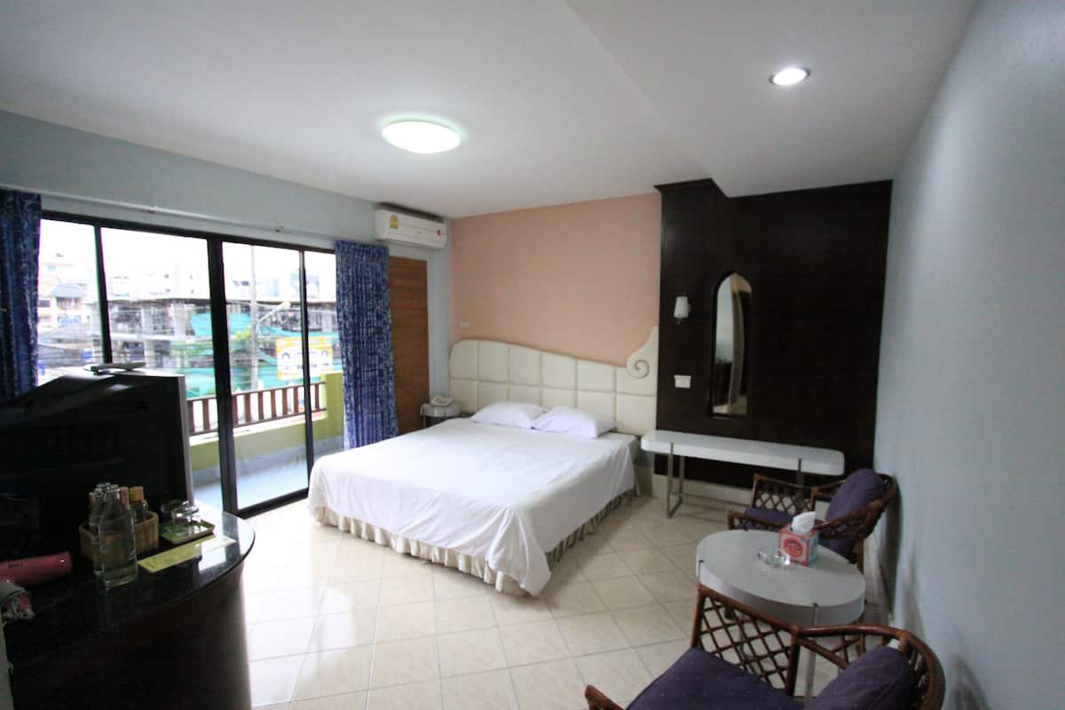 A hotel room with a bed, a desk, a chair, a small table, and a view of the outside.
