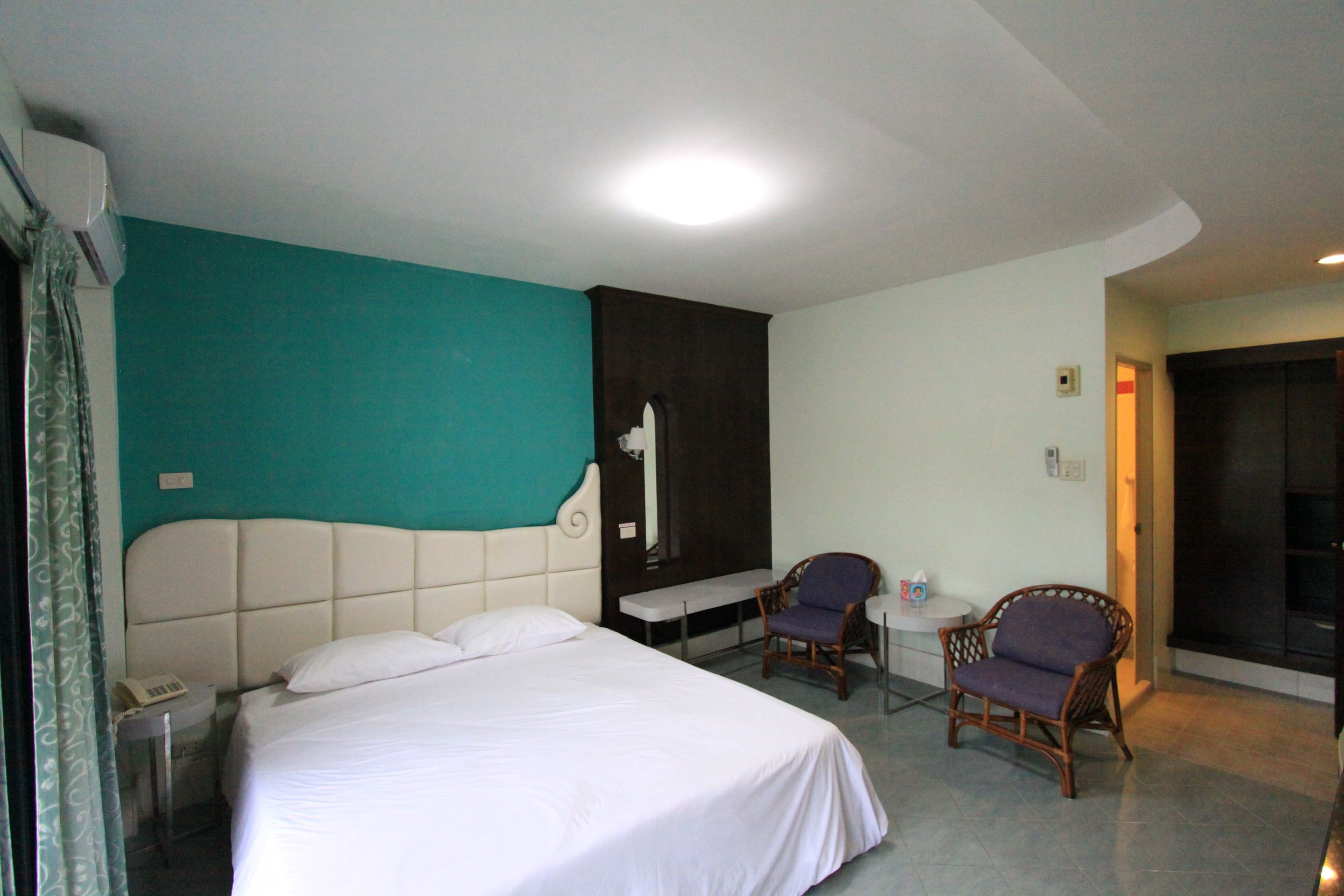 A hotel room with a large bed, two chairs, a small table, and a TV.