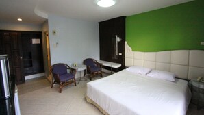 A hotel room with a bed, two chairs, a small table, and a green accent wall. - RangRong Hotel (Patong)