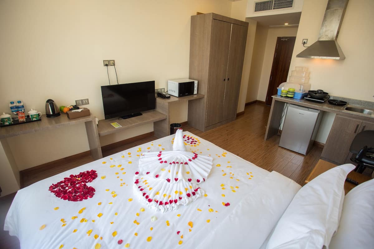 Habitación de hotel con cama, televisión, microondas, refrigerador pequeño y kitchenette.