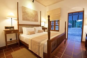 A four-poster bed with a wooden frame, a bedside table with a lamp, and a large window with a view of the outdoors. - EKHO Sigiriya (Sigiriya)
