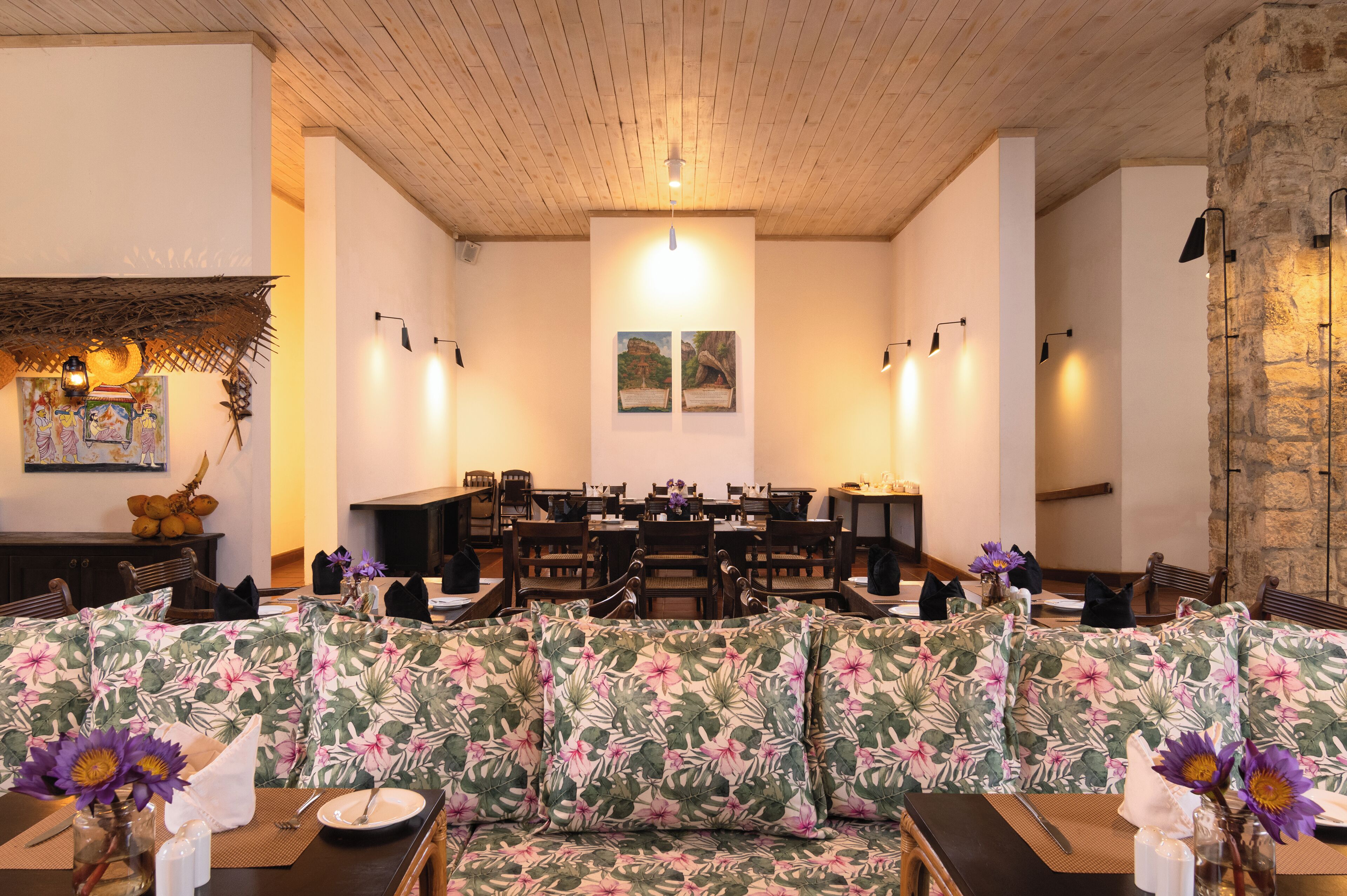 A dining area with a long table, chairs, and a floral sofa.