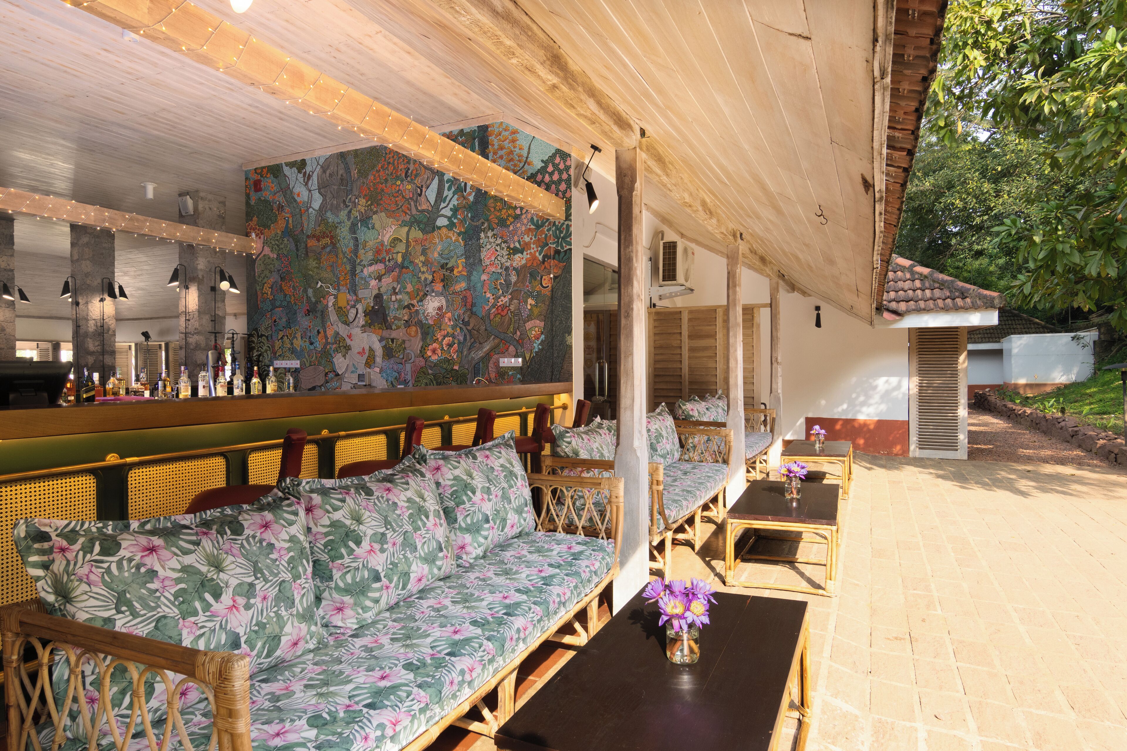 An outdoor seating area with wicker furniture and a colorful mural on the wall.