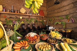 A room with a woven ceiling, shelves with various items, and a table with food and fruits. - EKHO Sigiriya (Sigiriya)