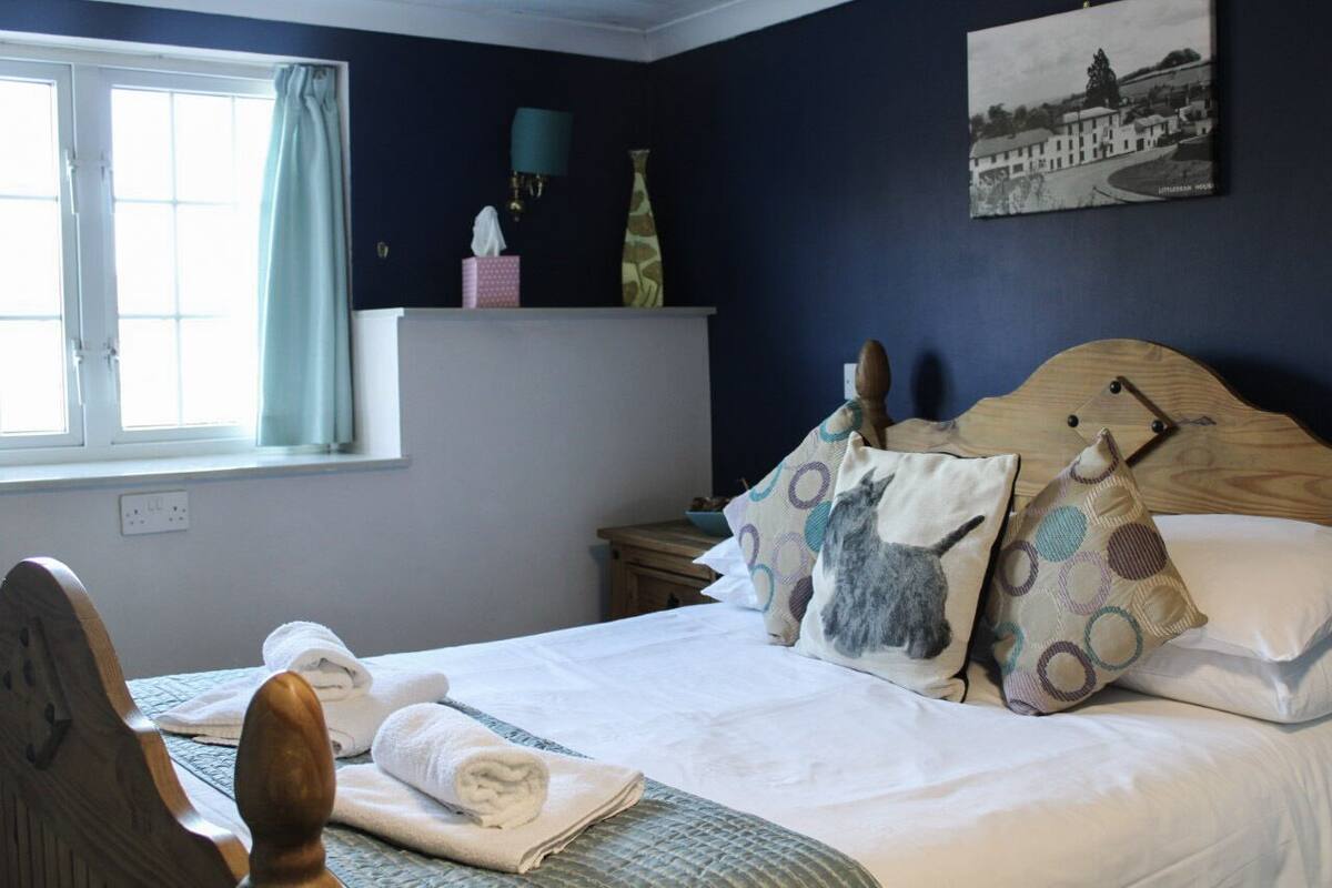 Un lit bien fait, avec des oreillers, une table de chevet avec une lampe, une fenêtre avec des rideaux et un tableau accroché au mur.