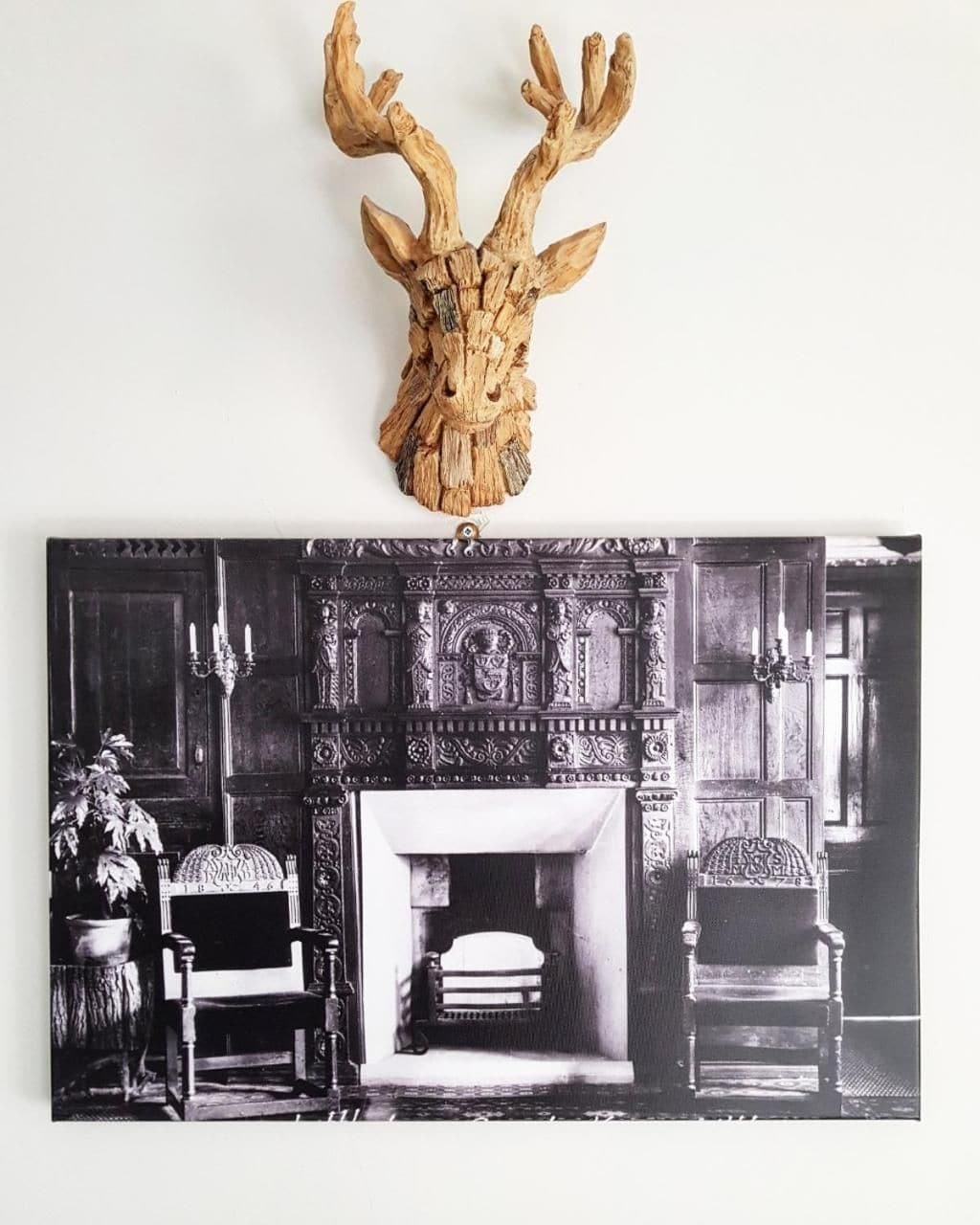 A fireplace with intricate carvings and a mounted deer head above it.