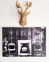 A fireplace with intricate carvings and a mounted deer head above it.