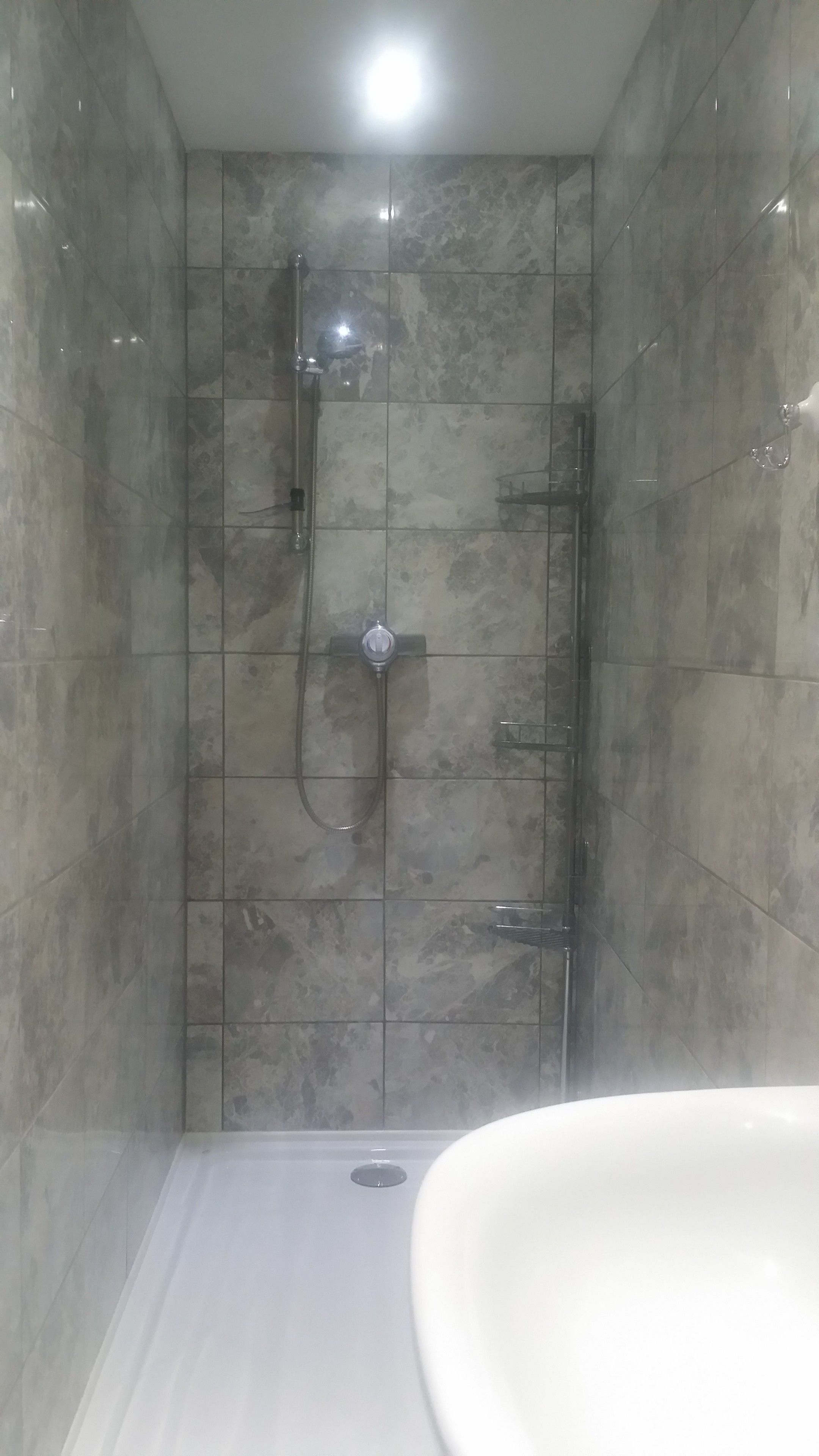 A bathroom with a shower, tiled walls, and a sink.