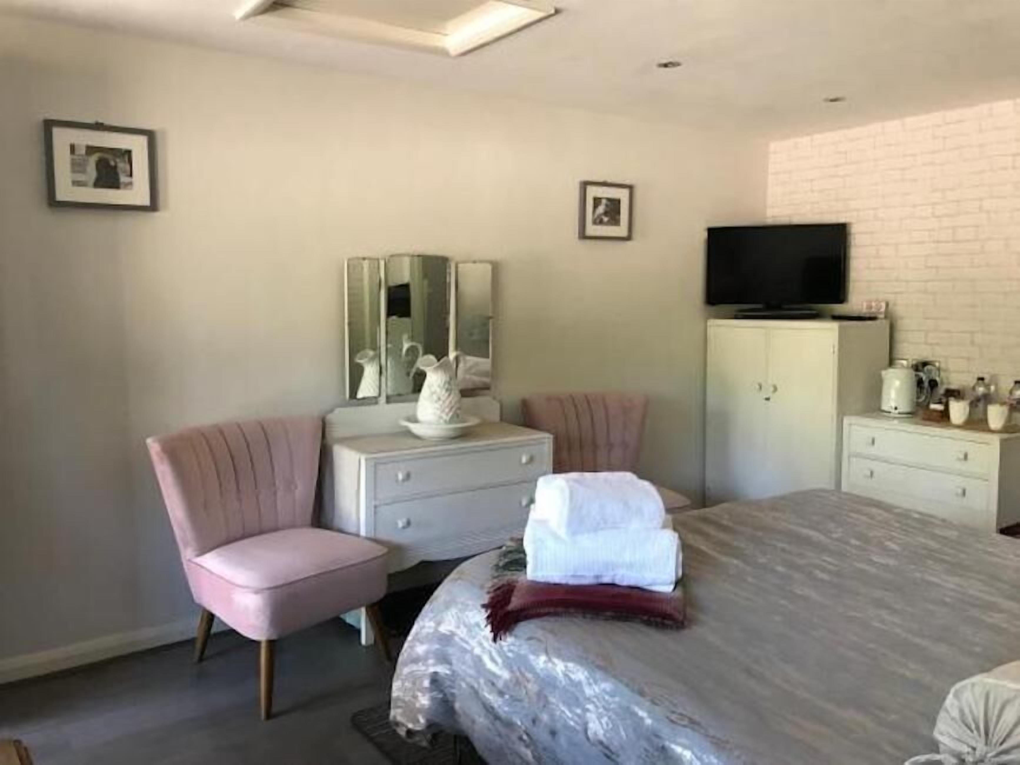 A bedroom with a bed, a vanity with a mirror, a television, and a cabinet.