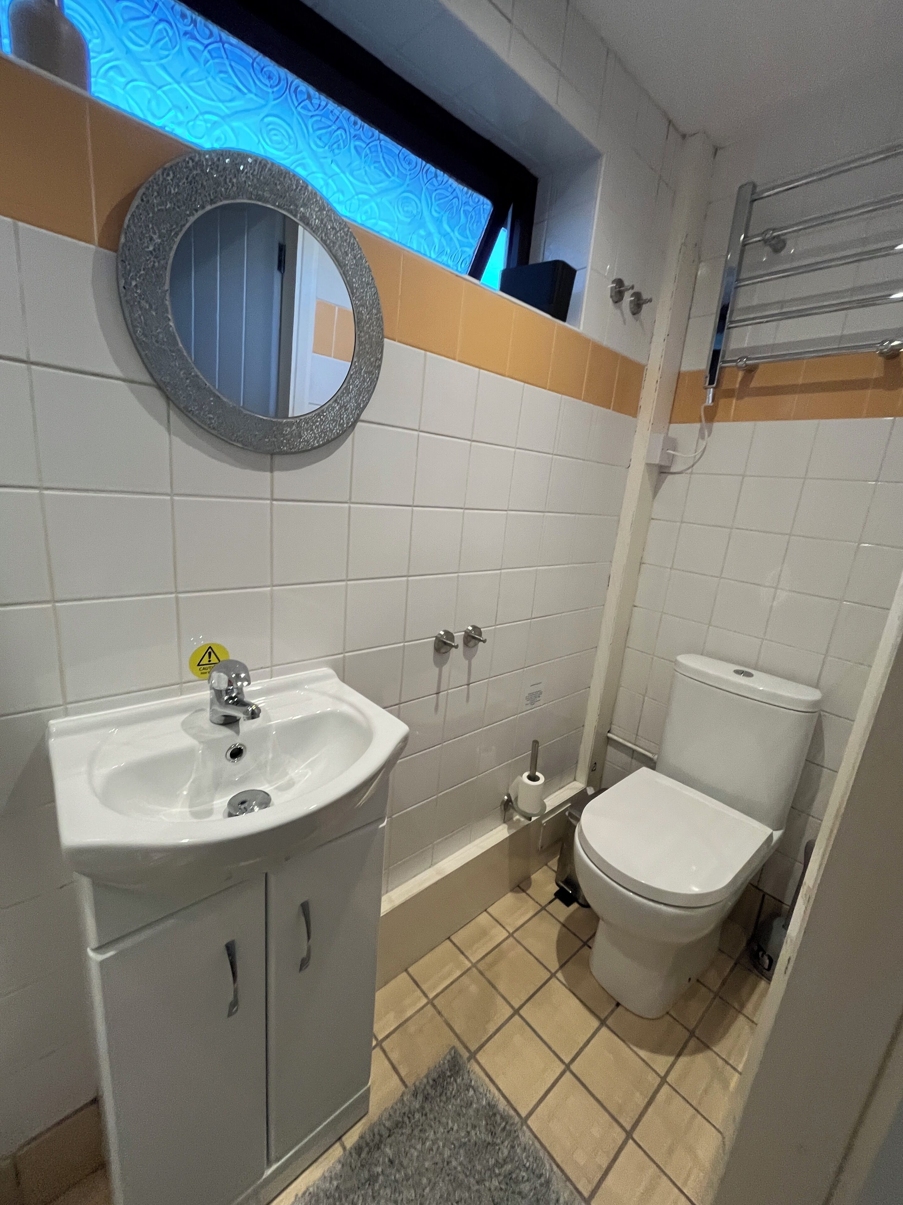 A bathroom with a sink, toilet, and mirror.