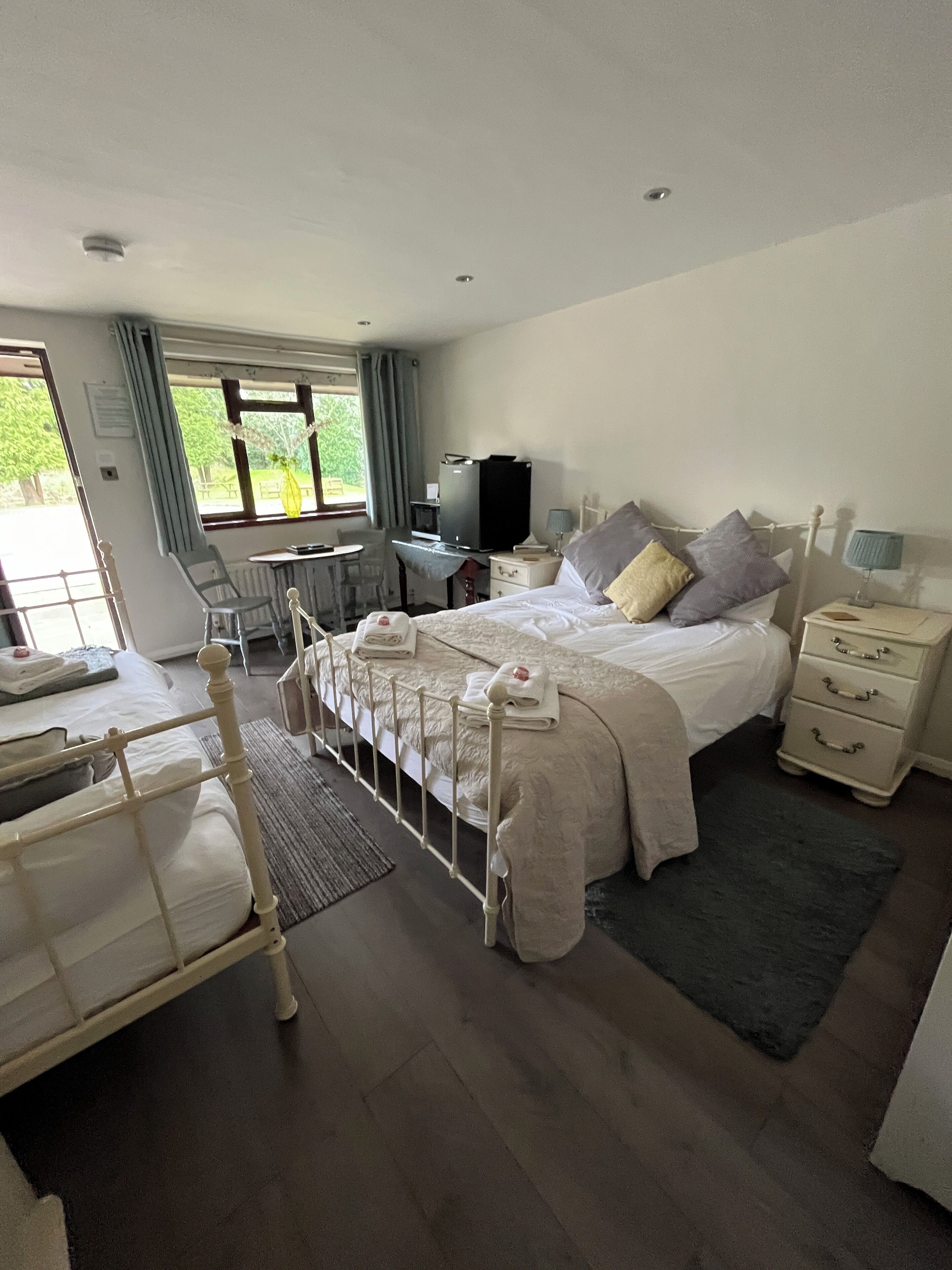 A bedroom with a bed, bedside tables, a desk, a chair, a television, and a window with curtains.