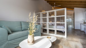 A modern living room with a teal sofa, a white coffee table, and a large window with a view of the city. - Agroturisme Son Vives - Adults Only (Ferreries)