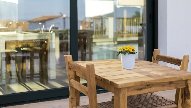 A wooden table with a potted plant on a balcony with a glass wall. - Agroturisme Son Vives - Adults Only (Ferreries)