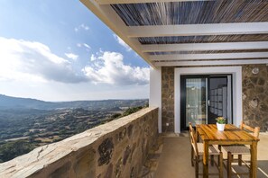 Mesa de madera con sillas en un balcón con vistas a un paisaje pintoresco.