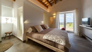 A bedroom with a wooden bed, a television, and a large window with a view. - Agroturisme Son Vives - Adults Only (Ferreries)