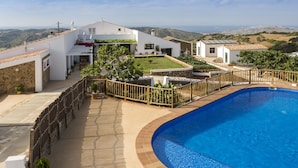 A modern villa with a swimming pool, a stone wall, and a view of the countryside. - Agroturisme Son Vives - Adults Only (Ferreries)