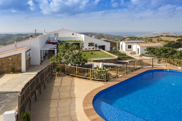 Una villa moderna con piscina, un muro de piedra y vistas al campo.