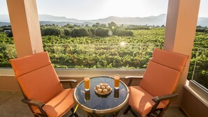 Un balcon avec deux chaises orange, une petite table ronde et un verre de jus d’orange.