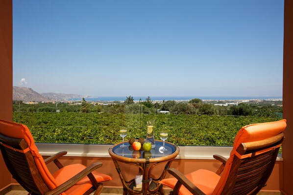 A balcony with two wooden chairs and a table with fruit and drinks. - Cretan Vineyard Hill Villa Private Pool, Panoramic View, Beautiful Vineyard (Malevizi)