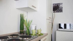 A modern kitchen with a stove, green plants, and a microwave on a white cabinet. - NL Smart (Rome)