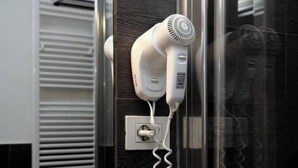 A hair dryer plugged into a wall socket in a bathroom. - NL Smart (Rome)