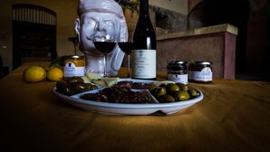 Une table avec une assiette d’olives, une bouteille de vin et un pot d’huile d’olive.