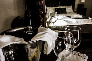 A minibar with a bottle and glasses, a bed with a white bedspread, and a bedside table with a lamp. - Tenuta del Gelso (Catania)