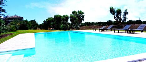 Una piscina al aire libre de temporada, sombrillas