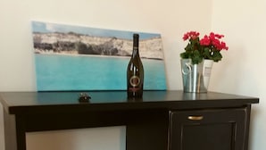 A dark wooden desk with a bottle and a vase of flowers on top. - La Trottoria (Otranto)
