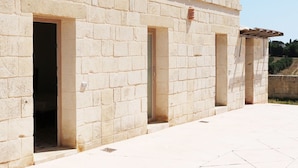 A building with a stone facade, multiple doorways, and a tiled ground. - La Trottoria (Otranto)