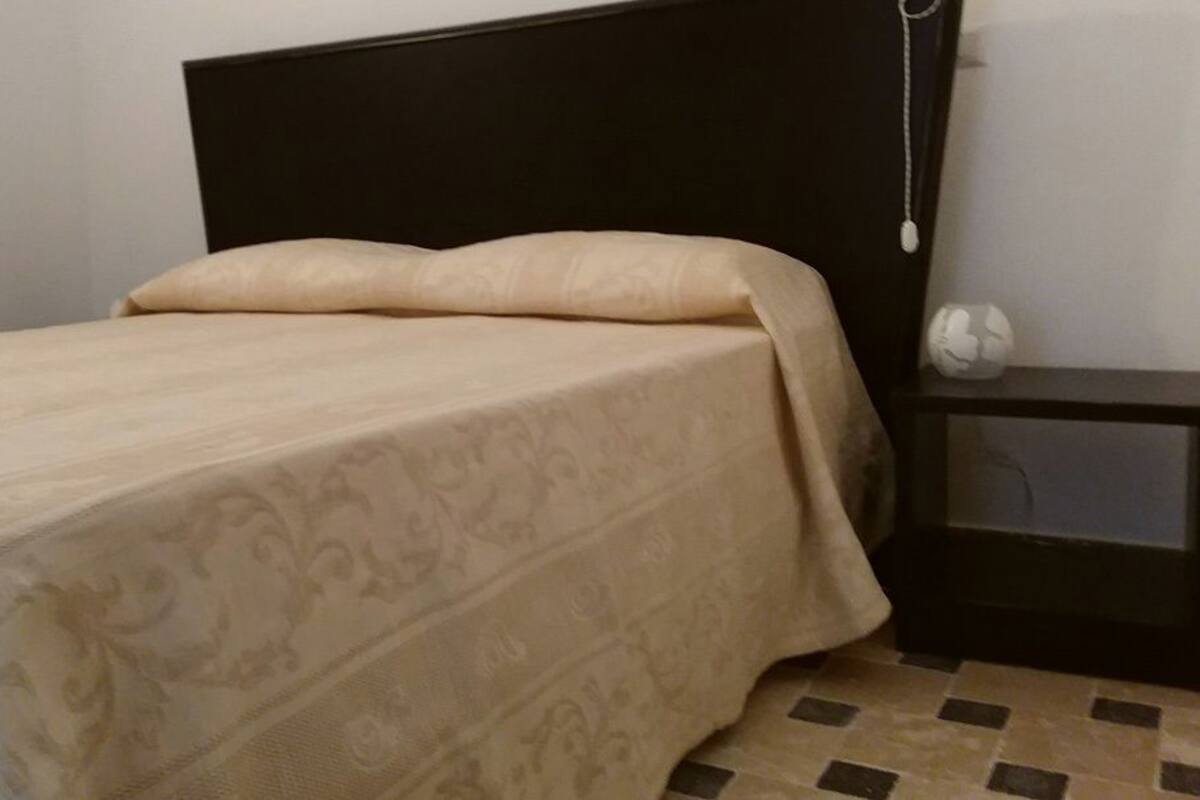 Una cama con una colcha estampada y un cabecero oscuro.