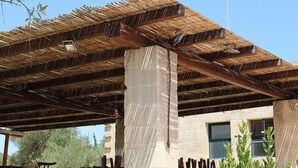 A covered outdoor area with a thatched roof, stone pillars, and windows. - La Trottoria (Otranto)