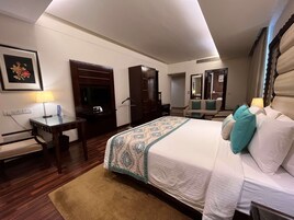 A hotel room with a large bed, a desk, a wardrobe, and a mirror.