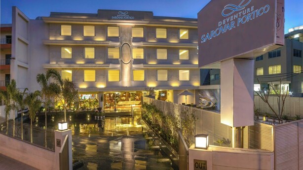 Un hotel amb una façana moderna, diversos balcons i una entrada ben il·luminada.