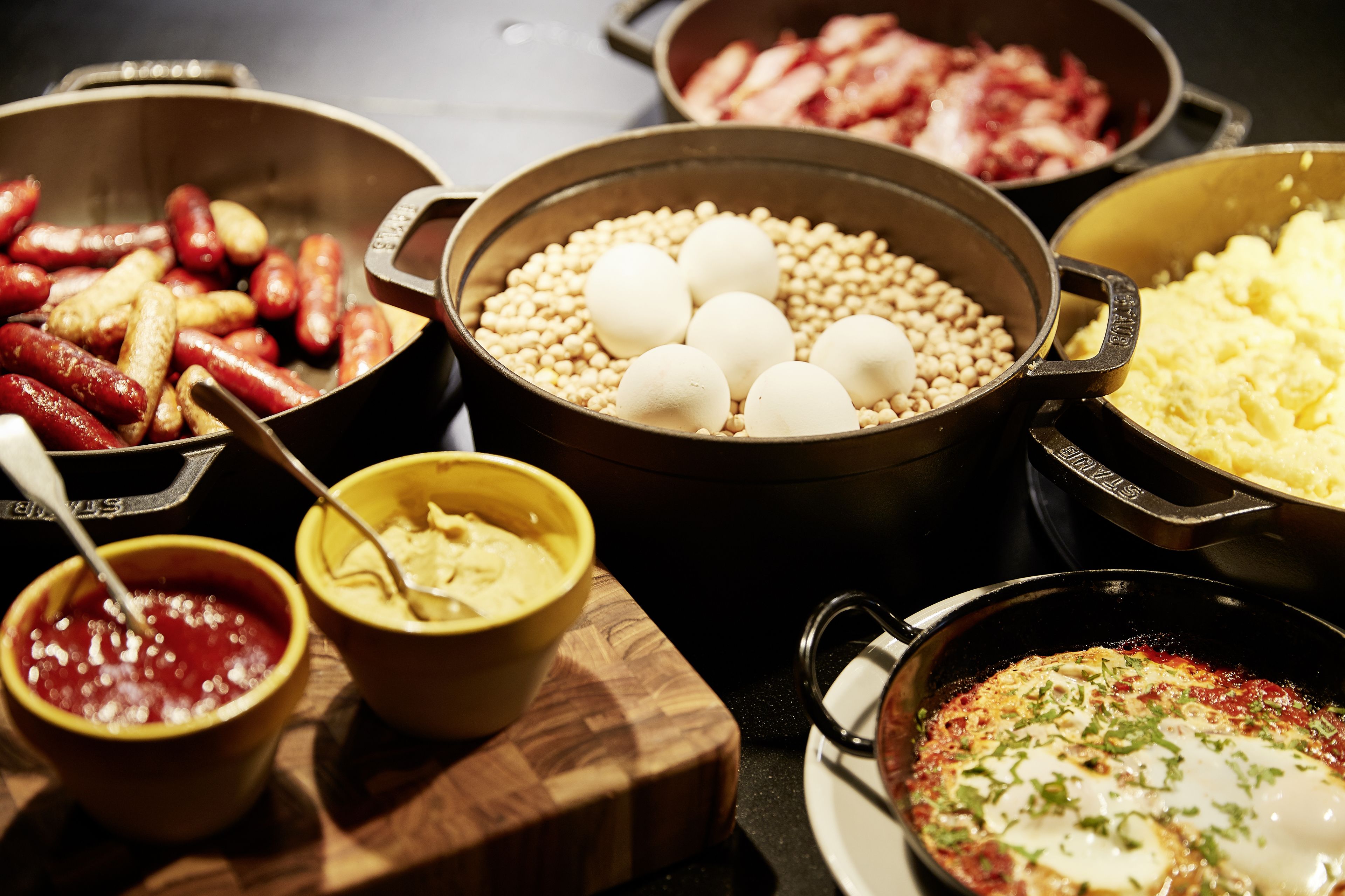 A variety of food items including sausages, boiled eggs, and a dish with a poached egg on top.