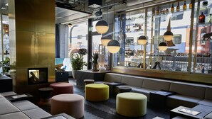 A modern interior with seating areas, a fireplace, and a view of a train outside. - 25hours Hotel Zurich Langstrasse (Zürich)