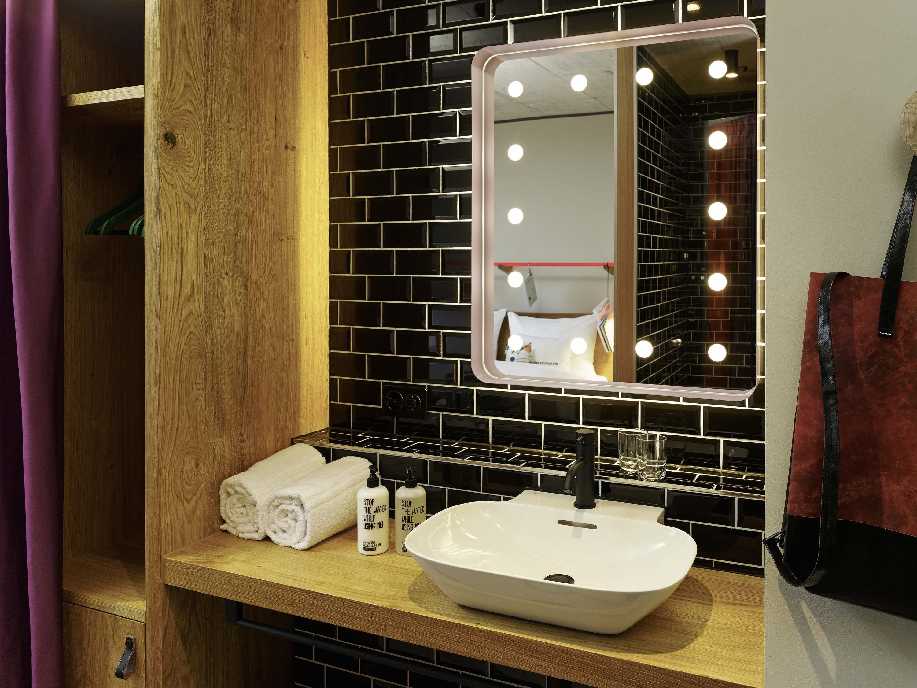 Un baño con tocador, espejo con luces, lavabo y toalla.