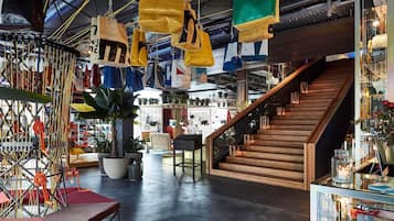 An indoor shopping area with a staircase, hanging bags, and various items on display.