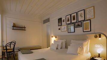 Habitación de hotel ordenada con cama, mesita de noche, lámpara y cuadro colgado en la pared.