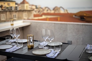 Une table à manger dressée avec des assiettes, des verres et des couverts, donnant sur un panorama urbain.