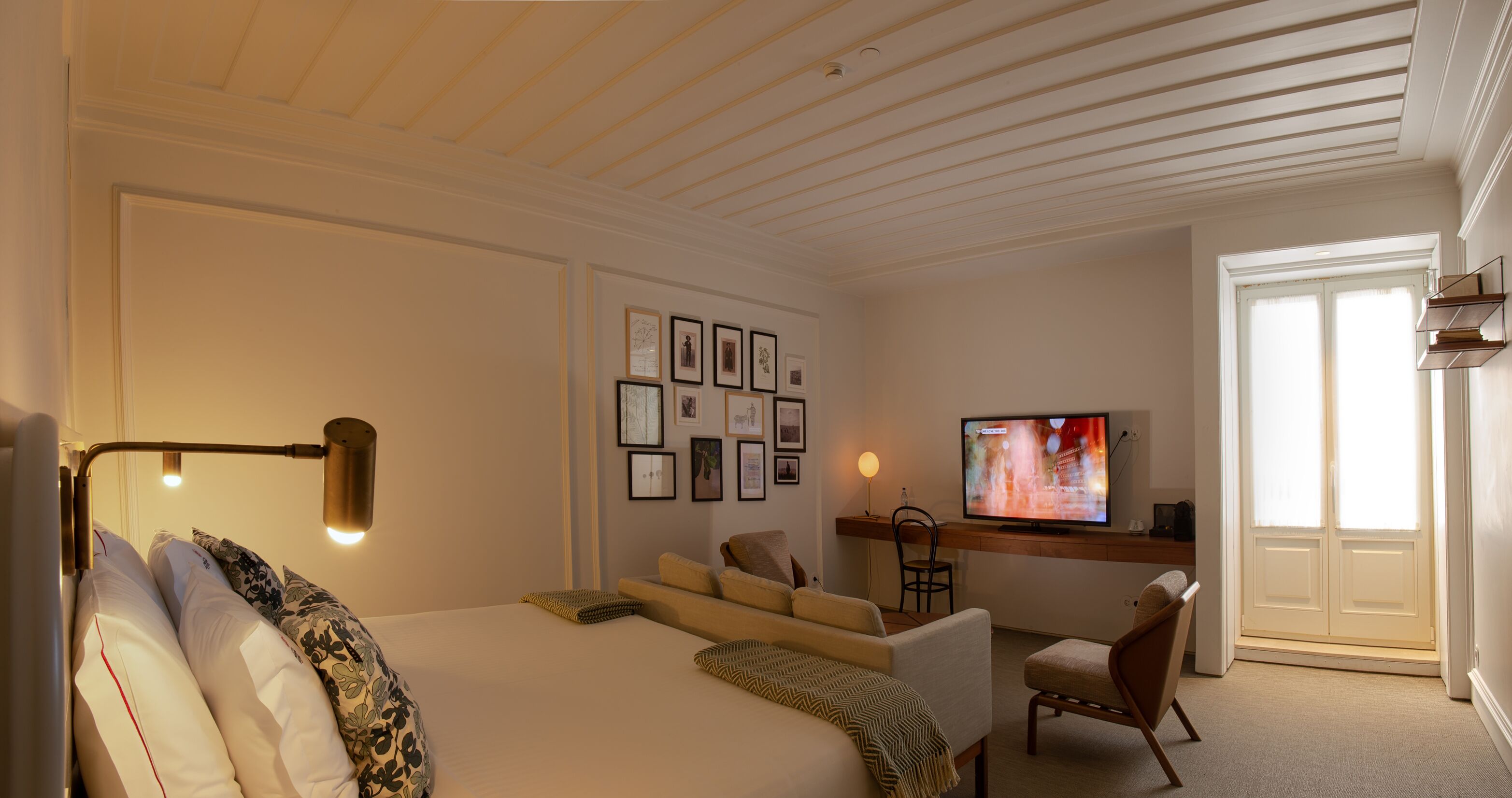 Un dormitorio con una cama grande, un escritorio, un televisor y cuadros en la pared.