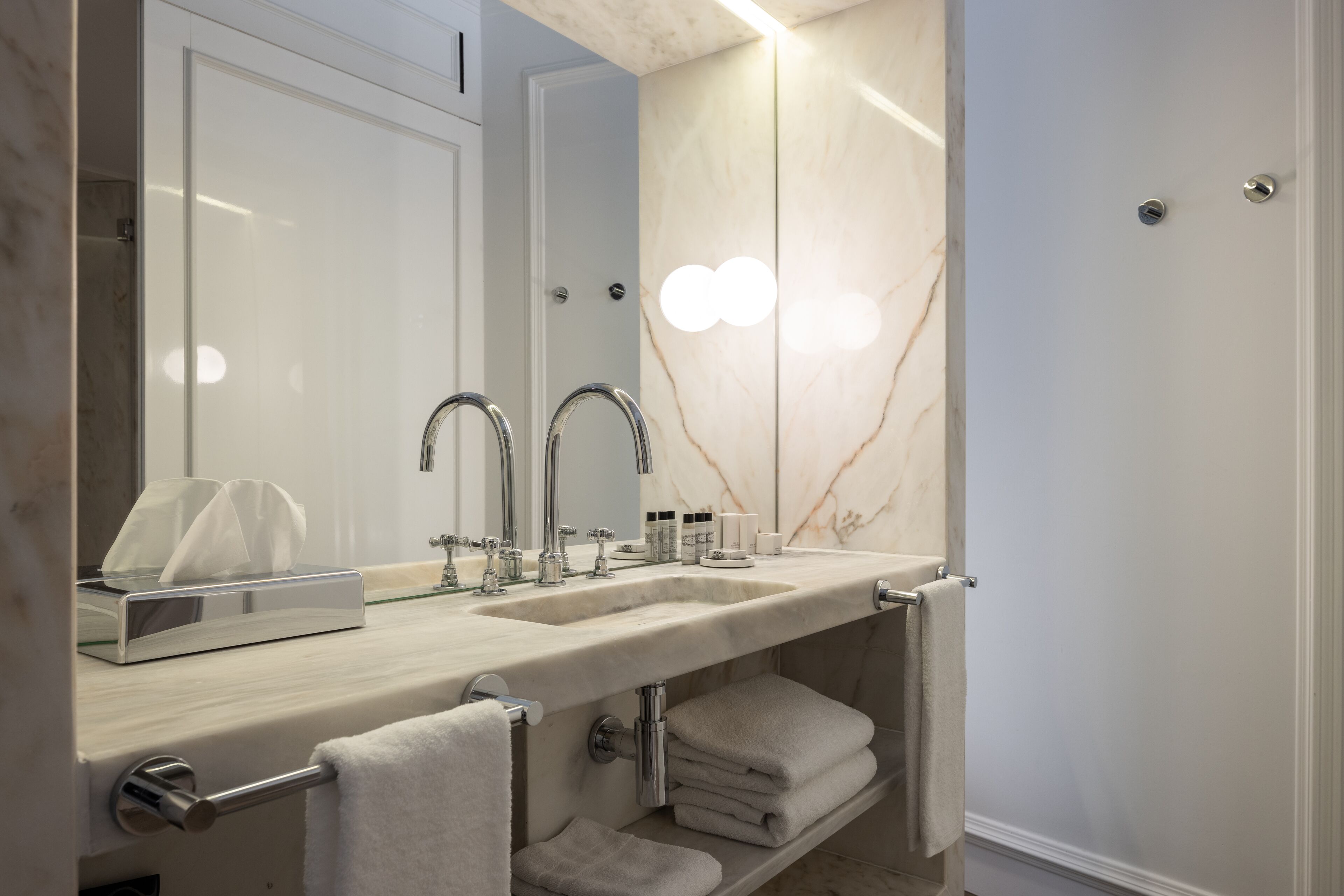 Un bagno moderno con una vanità in marmo, due lavabi e un grande specchio.