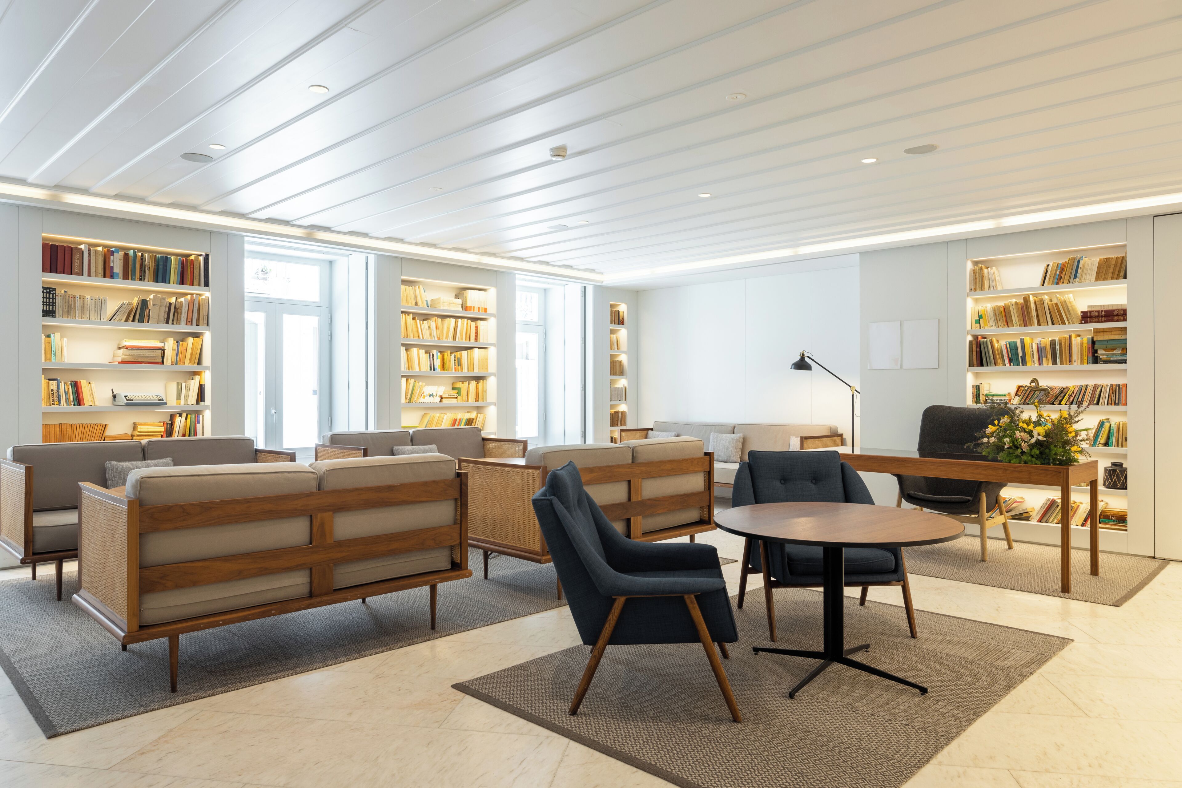 A modern library with bookshelves, sofas, and a round table.